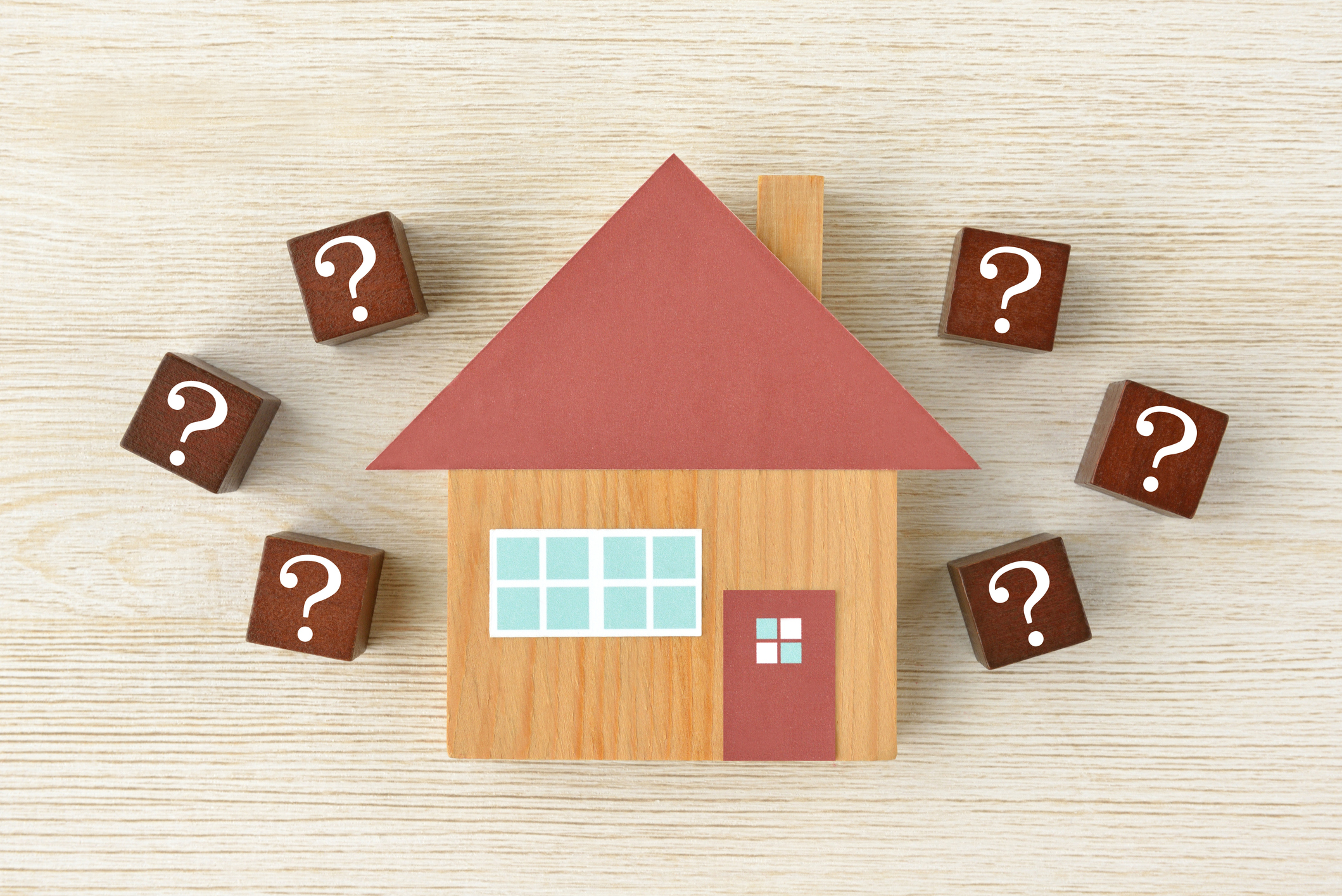 A wooden house surrounded by wooden blocks with question marks on them.