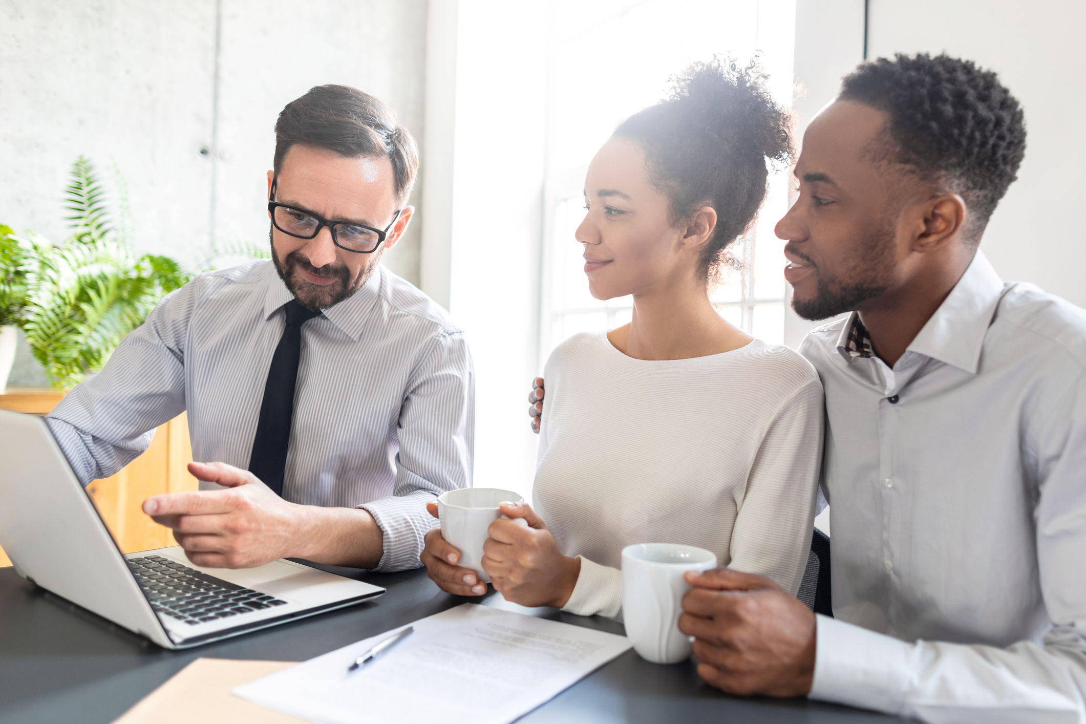 A mortgage broker reviews renewal options with a couple over coffee, providing professional guidance and informed decision-making in the mortgage renewal process in Canada.